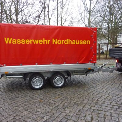 Anhänger der Wasserwehr in der Seitenansicht mit der Aufschrift auf roter LKW-Plane "Wasserwehr Nordhausen"